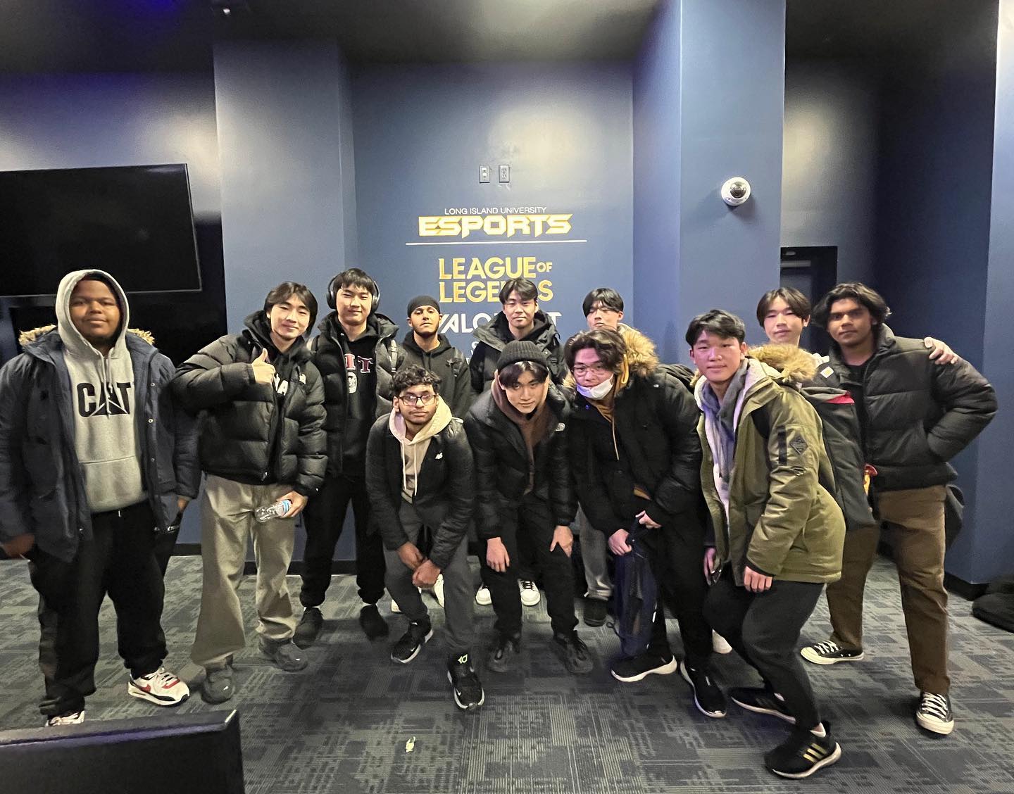 Larger group photo of about a dozen people in front of the esports banner