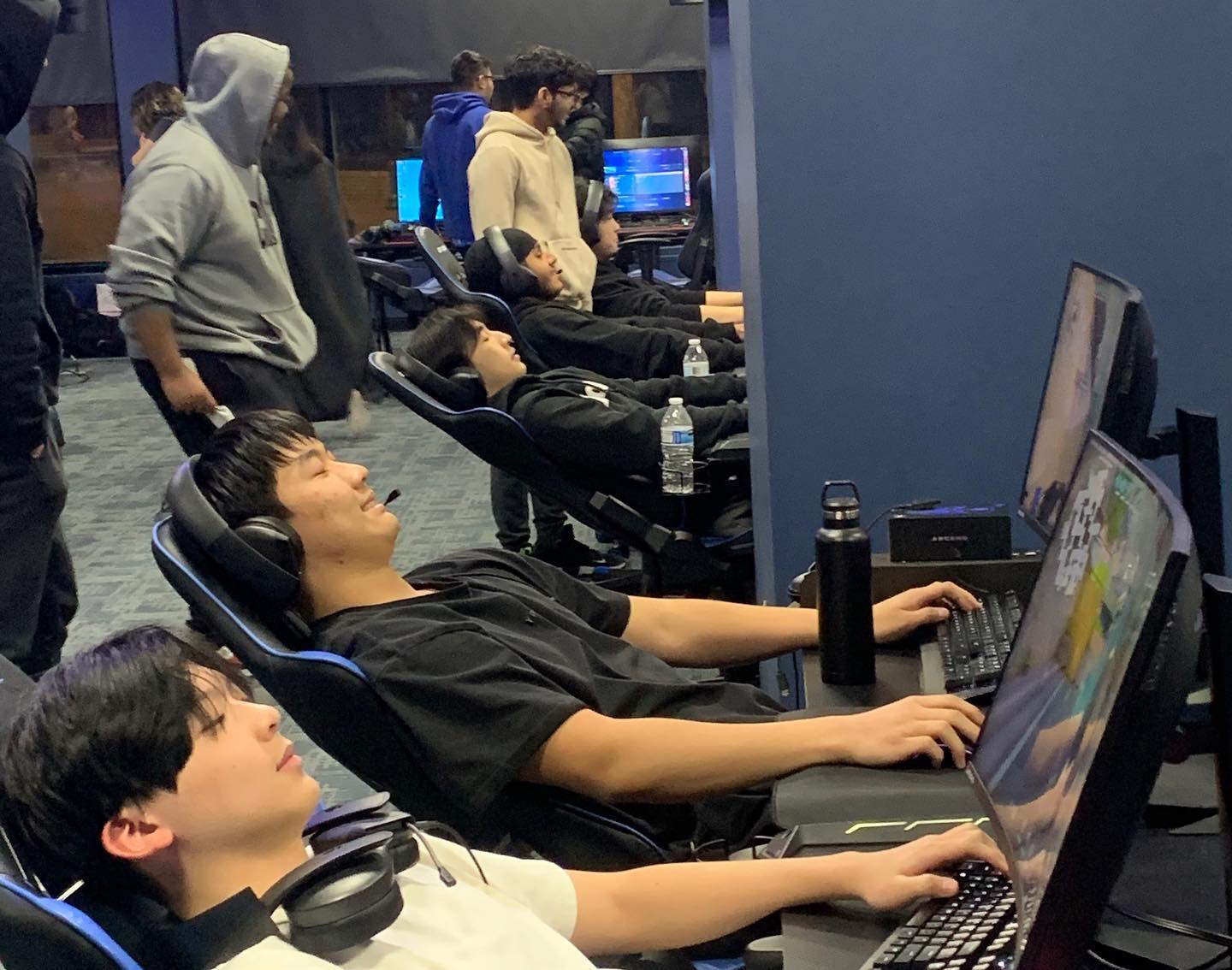 Players reclined at their stations mid-match, headphones on