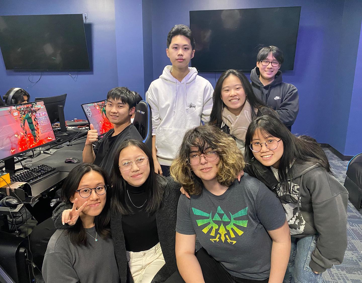 Seven friends gathered in front of the gaming monitors for a group shot