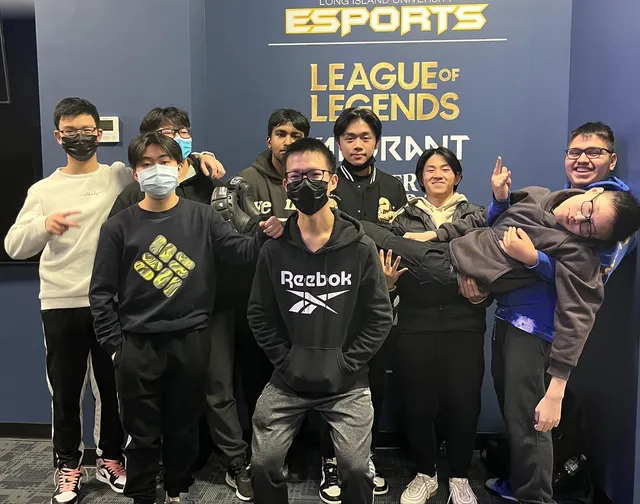 Group photo at the banner, one teammate being playfully carried