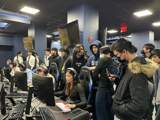 Crowd of students gathered around the gaming stations watching a match live